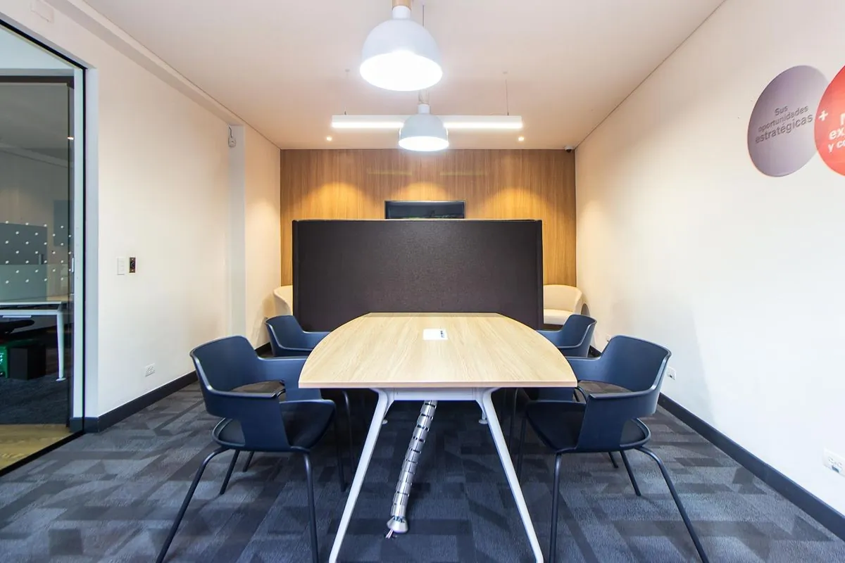 Sala de reunião com mesa oval de madeira e cadeiras