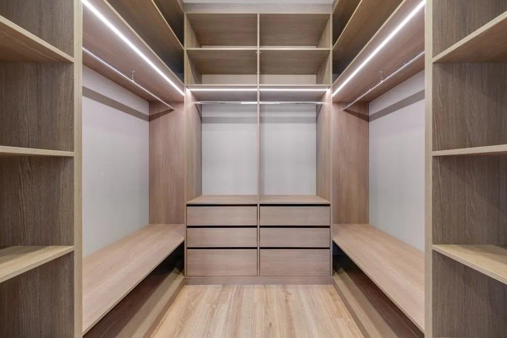 Closet planejado com cabideiros, gavetas e prateleiras iluminadas