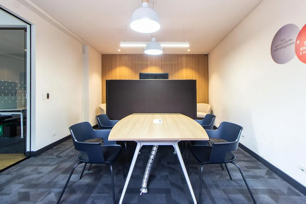 Sala de reunião com mesa oval de madeira e cadeiras
